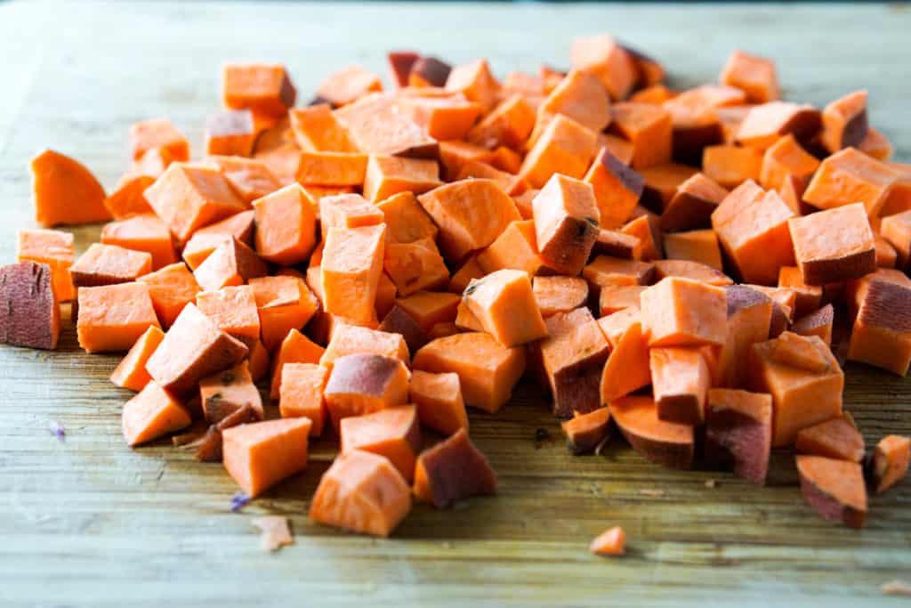 uniformly diced sweet potatoes on cutting board, skins on