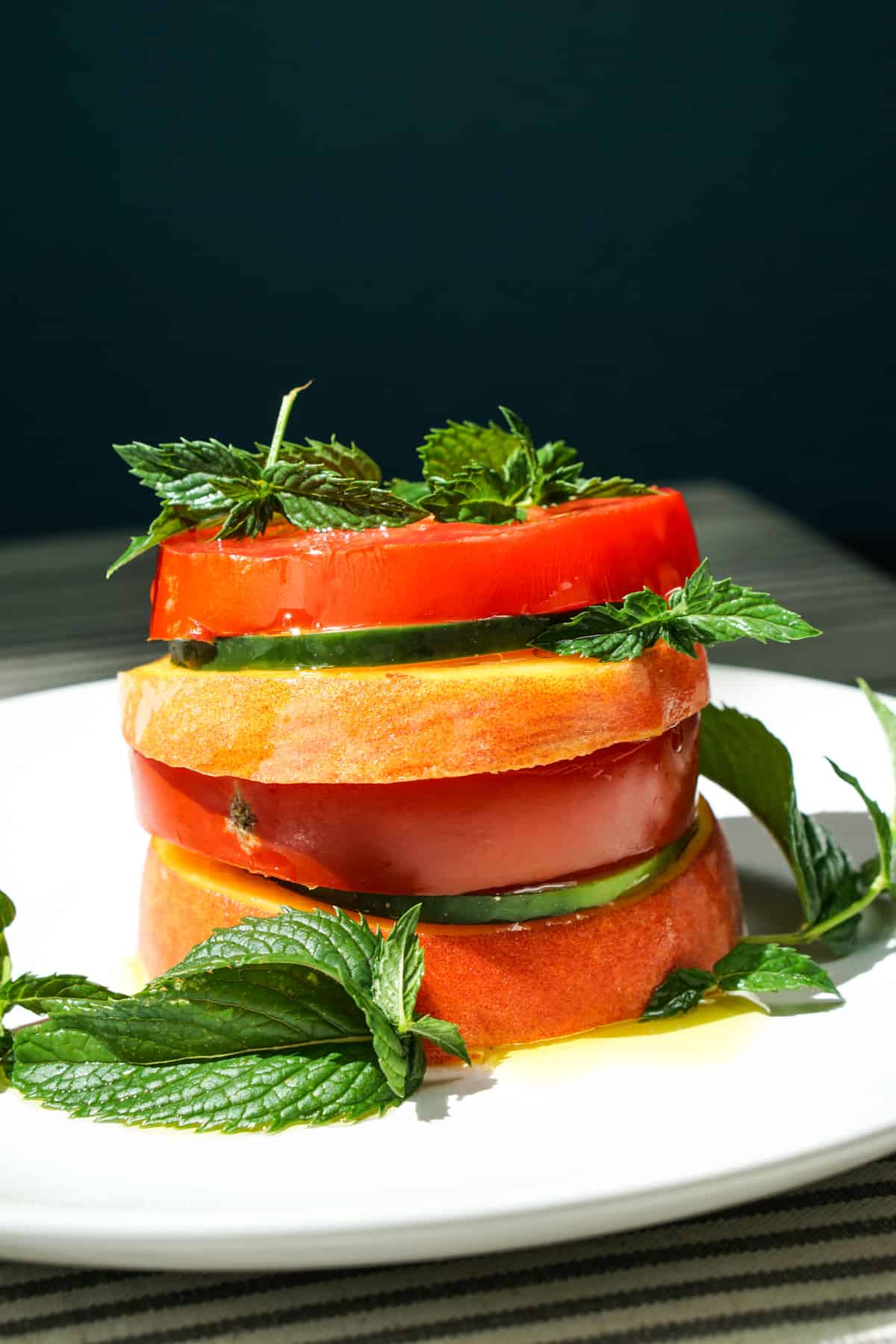 Peach Tomato Mint Salad Stack Recipe - Simply slice fresh peaches, tomatoes and cucumbers, stacking with mint to create this great appetizer, light meal or side salad. This will definitely be a recipe to impress your friends at your next barbq or family dinner!