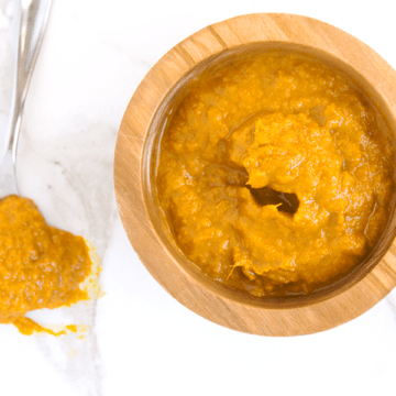 orange Ginger Turmeric Honey Chili Sauce with Dried Red Chilies is spicy, tangy and fresh, making a great marinade, dip, and homemade hot sauce. It's also chocked full of superfoods. in wooden bowl next to spoon dripping sauce on white marble
