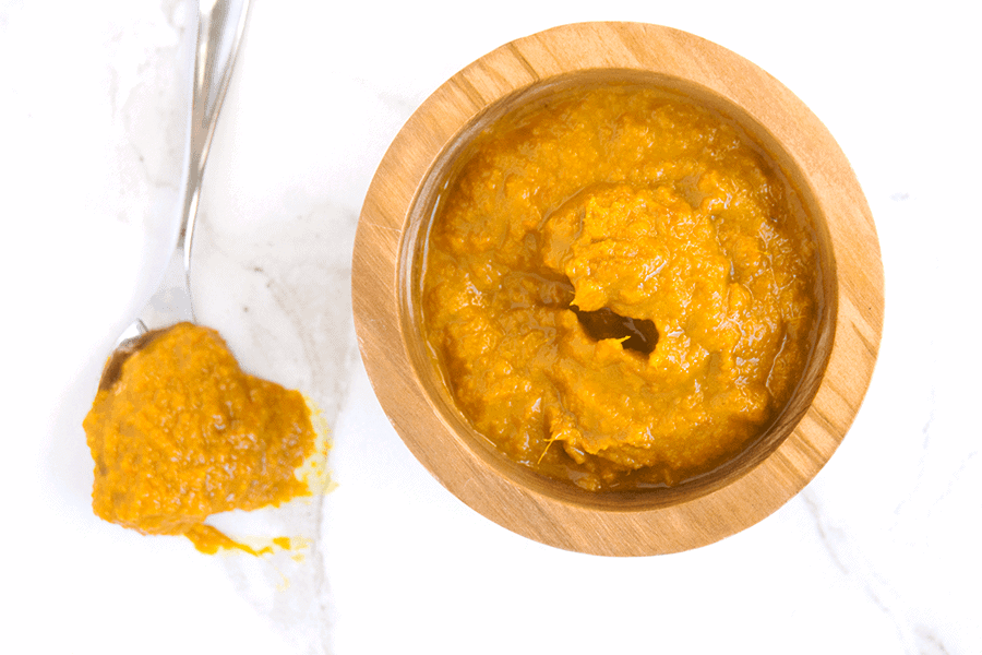 orange Ginger Turmeric Honey Chili Sauce with Dried Red Chilies is spicy, tangy and fresh, making a great marinade, dip, and homemade hot sauce. It's also chocked full of superfoods. in wooden bowl next to spoon dripping sauce on white marble