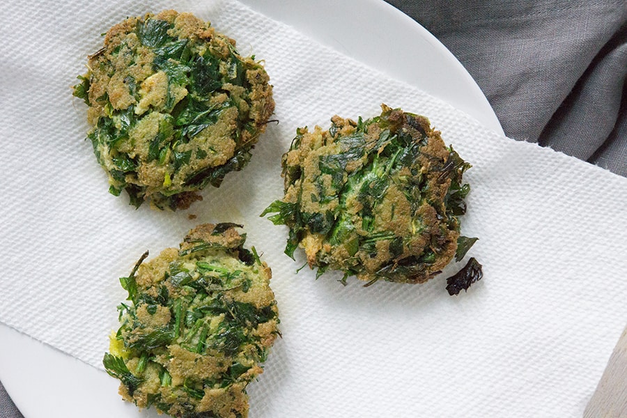Just fried celery pulp and parsley patties on a white plate
