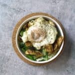 White bowl on cork circle on cement with sauteed cabbage and turnip greens with harissa roasted turnips and broth poached eggs