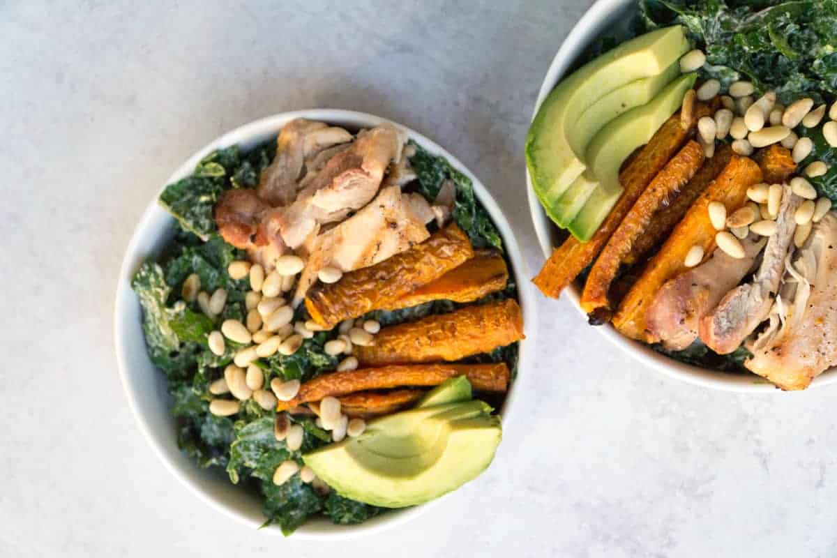 Superfood Kale Caesar salad with avo, chicken thighs, pine nuts, and creamy tahini cashew Caesar dressing
