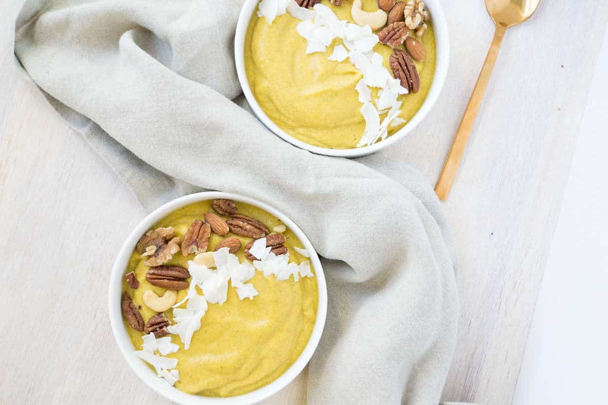Orange Pumpkin smoothie bowls topped with roasted nuts and coconut flakes, with linen napkins