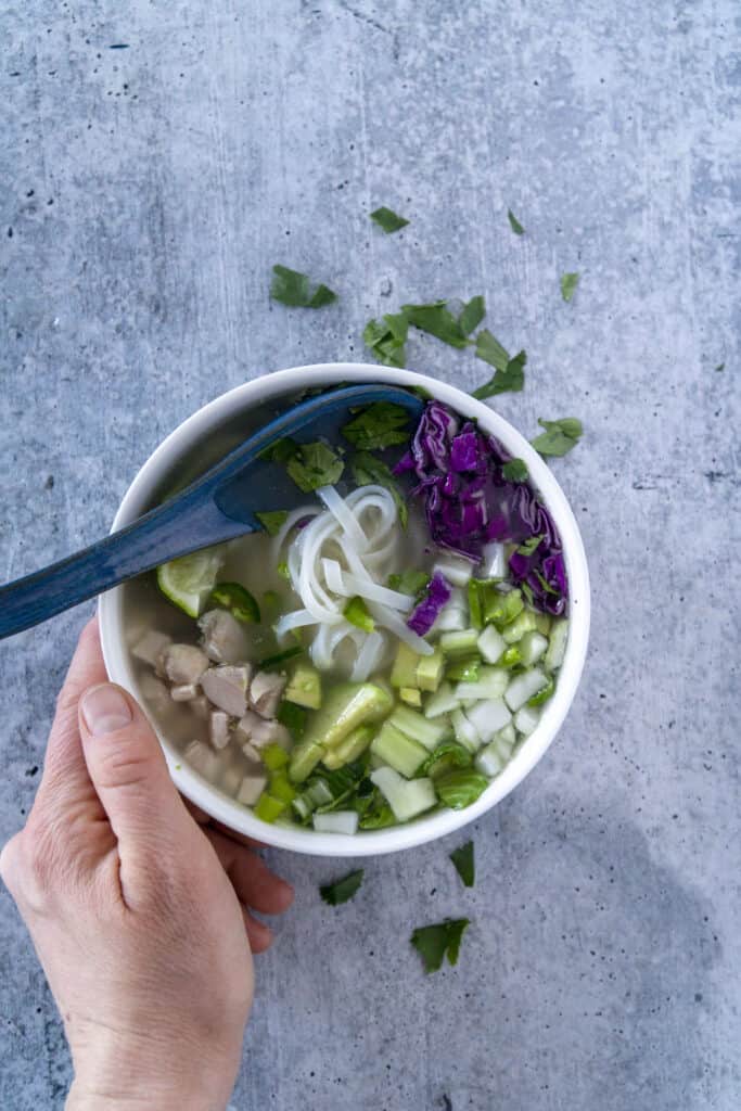 Hand and spoon on Gluten Free Pho Bowl