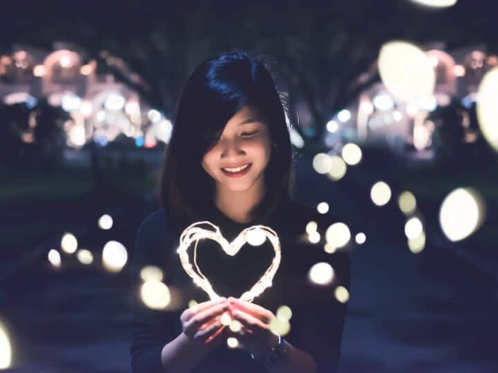 girl holding light-up heart in dark street