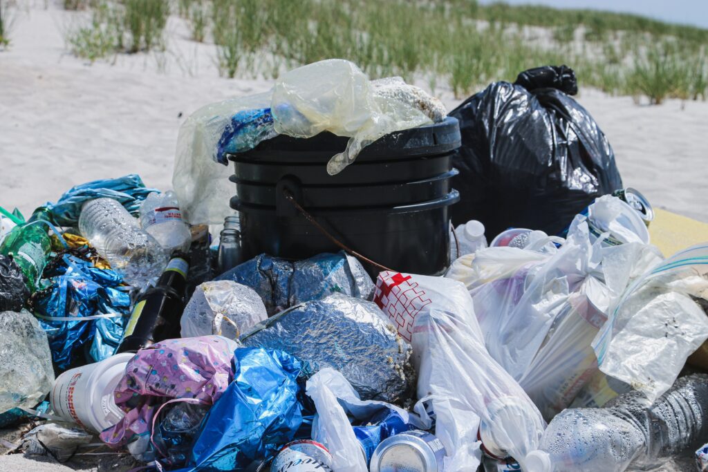 Overflowing plastic bags of trash with plastic spilling out all over the beach