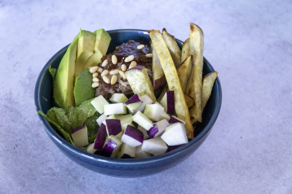 Side view of Fig Tahini Burger bowl with sweet potato fries, kohlrabi and avocado
