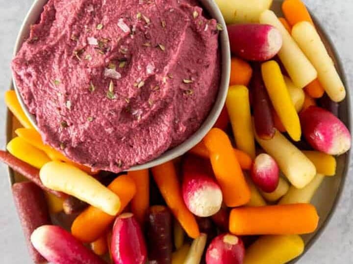 Beet hummus with rainbow carrots on concrete counter 2