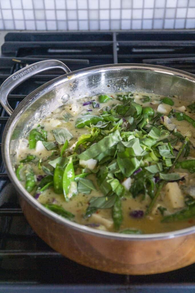 Green curry with herbs in a copper pan on the stove