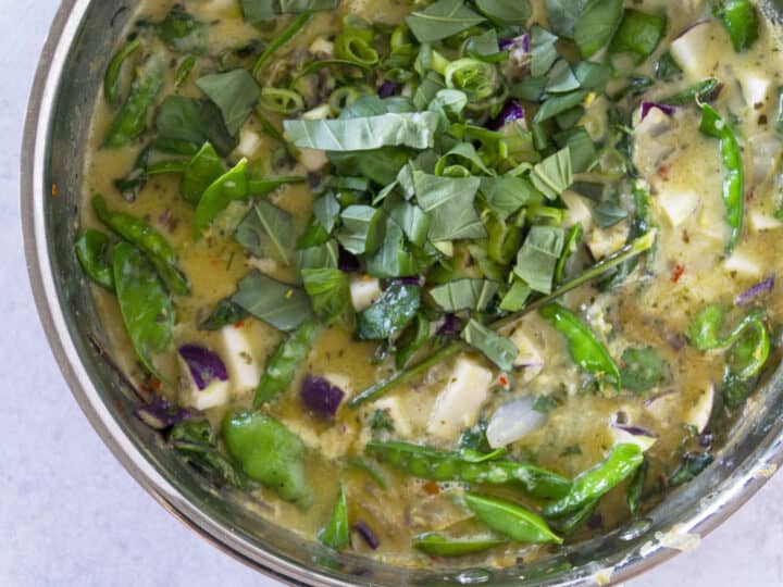 Green curry with snap peas and herbs in copper pot